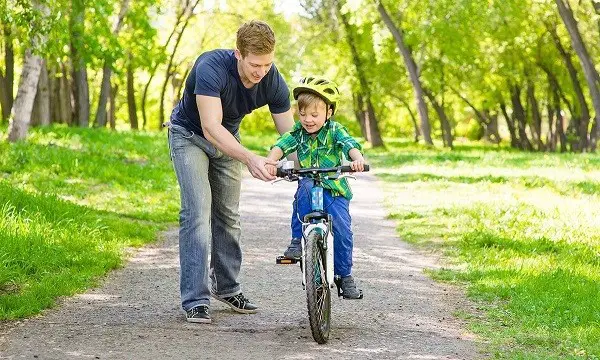 faire monter un enfant sur un vélo à deux roues